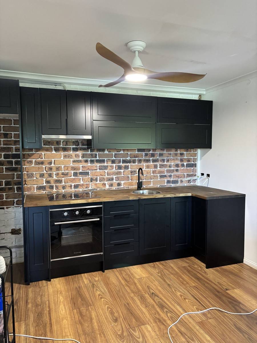Dark kitchen installation with brick splashback